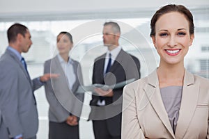 Smiling businesswoman posing while colleagues talking together