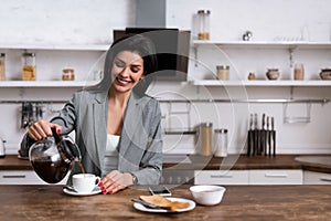 Smiling businesswoman pouring coffee in cup