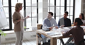 Smiling businesswoman presenting project details to coworkers.