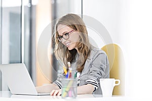 Smiling businesswoman reading an email on laptop in office