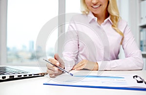 Smiling businesswoman reading papers in office