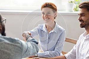 Smiling businesswoman shaking hand of African American colleague at briefing