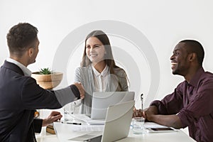 Smiling businesswoman shaking hand of male partner at group meet