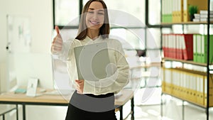 Smiling businesswoman showing thumb up gesture in office