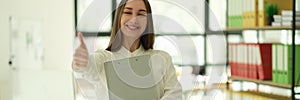 Smiling businesswoman showing thumb up gesture in office