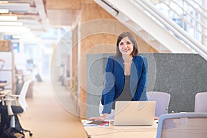 Smiling businesswoman standing at her desk in bright modern offi