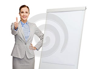 Smiling businesswoman standing next to flip board