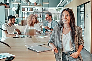 Smiling businesswoman standing at table in office and looking away