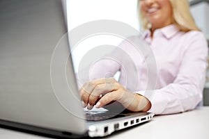 Smiling businesswoman or student typing on laptop