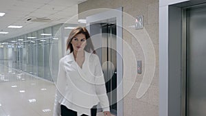 Smiling businesswoman in suit stepping out of elevator