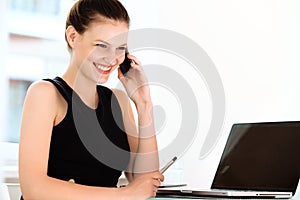 Smiling businesswoman talking on mobile phone in a office