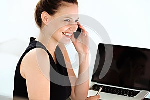 Smiling businesswoman talking on mobile phone in a office