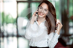 Smiling businesswoman talking on the phone at the office.
