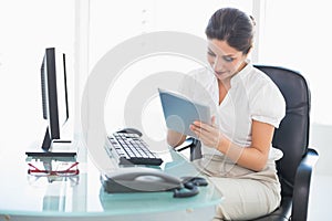 Smiling businesswoman using her digital tablet at desk