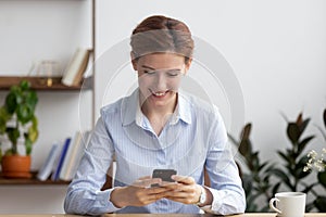 Smiling businesswoman using mobile phone at workplace during break