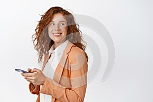 Smiling businesswoman using smartphone, looking behind her at logo banner. Cellular technology concept