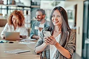 Smiling businesswoman using smartphone in modern office interior