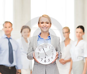 Smiling businesswoman with wall clock