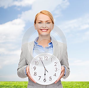 Smiling businesswoman with wall clock