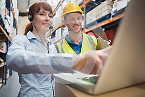 Smiling businesswoman wearing headset using laptop