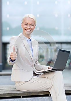 Smiling businesswoman working with laptop outdoors