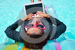 Smiling businesswoman working on laptop in pool