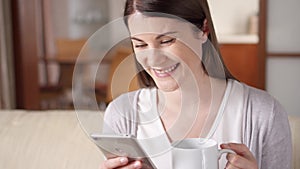 Smiling businesswoman working on mobile phone at home drinking coffee. Home-office concept