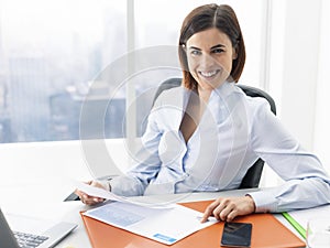 Smiling businesswoman working in the office and checking charts photo
