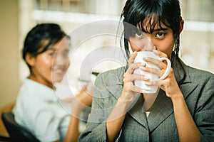 Smiling businesswomen drink coffee in office