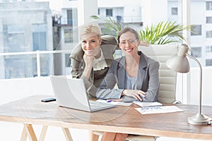 Smiling businesswomen looking at camera and working together