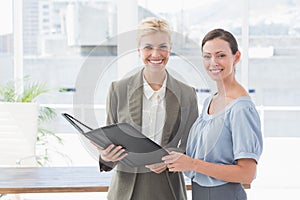 Smiling businesswomen looking at camera and working together
