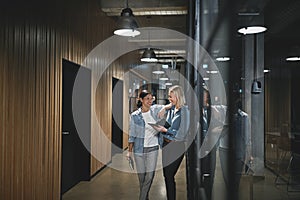 Smiling businesswomen talking together in an office hallway