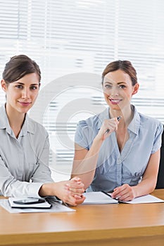 Smiling businesswomen working together and looking at camera