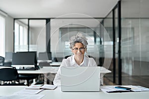 Smiling busy middle aged woman using laptop working in business office.