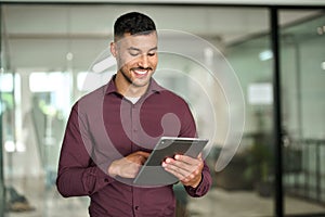 Smiling busy young business man manager using tablet standing in office.