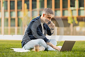 Smiling busy young european guy in casual enjoy lifestyle, work on laptop, call by phone