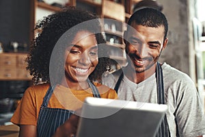 Smiling cafe owner in apron looking at digital tablet