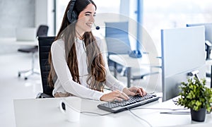 Smiling call center agent working at helpdesk, tracking, monitoring and responding to communications from customers.