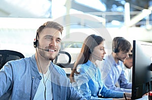 Smiling call center employees sitting in line with their headset