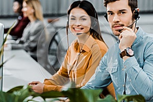 Smiling call center operators in headsets looking at camera