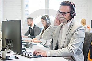 Smiling call center worker with headset giving technical support to customers