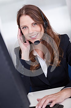 Smiling call center worker sitting typing