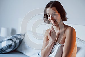 Smiling for the camera. Time for a make up. Woman sits on the bed and use cosmetics to clean her skin