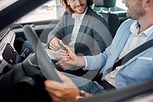 Smiling car dealer selling car to young man