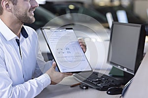 Smiling car dealer showing daily agreement and receipt to buyer during transaction