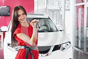 Smiling car salesman handing over your new car keys, dealership and sales concept. Happy girl the buyer