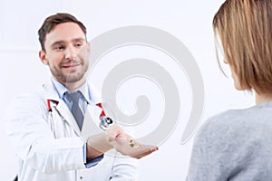 Smiling cardiologist giving pills to the patient