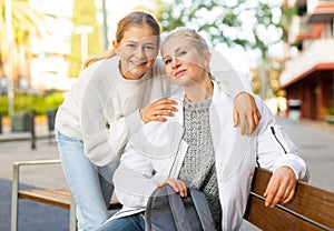 Smiling carefree teenage girl posing with mother on city street