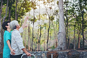 Smiling caregiver Senior nurse take care a Senior patient in walker for relaxing and looking around park