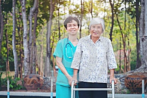 Smiling caregiver Senior nurse take care a Senior patient in walker for relaxing and looking around park